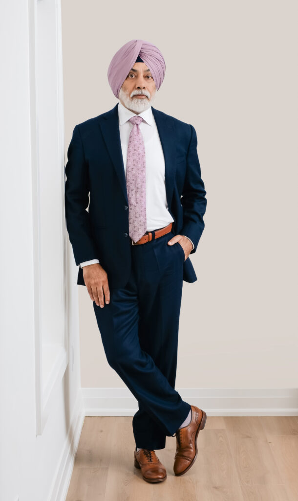 Portrait of realtor Jaswinder Singh leaning against a wall